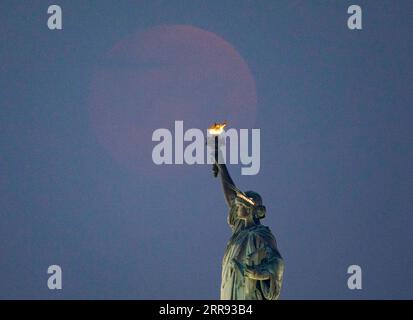 210526 -- NEW YORK, 26. Mai 2021 -- Ein Mond wird in der Wolke über der Freiheitsstatue in New York, USA, gesehen, 26. Mai 2021. Am Mittwoch konnte in Teilen der Vereinigten Staaten ein Supermond beobachtet werden. U.S.-NEW YORK-MOON WangxYing PUBLICATIONxNOTxINxCHN Stockfoto