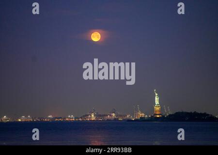 210526 -- NEW YORK, 26. Mai 2021 -- Ein Mond wird über der Freiheitsstatue in New York, den Vereinigten Staaten, gesehen, 26. Mai 2021. Am Mittwoch konnte in Teilen der Vereinigten Staaten ein Supermond beobachtet werden. U.S.-NEW YORK-MOON WangxYing PUBLICATIONxNOTxINxCHN Stockfoto