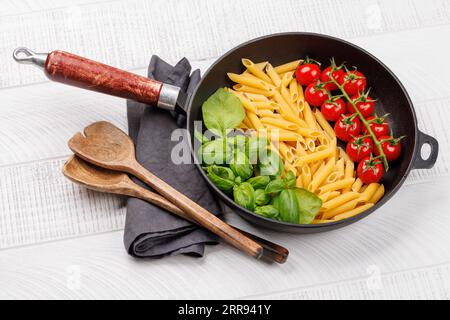 Eine lebendige Darstellung der italienischen Flagge mit Pasta, Basilikum und Tomaten, wunderschön präsentiert in einer Pfanne Stockfoto