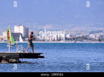 210528 -- CAGLIARI ITALIEN, 28. Mai 2021 -- Ein Mann fischt am 28. Mai 2021 am Meer in Cagliari, Sardinien, Italien. Alle italienischen Regionen sind seit Montag gelb geworden, was ein geringes Ansteckungsrisiko und das niedrigste Maß an Anti-COVID-19-Einschränkungen anzeigt, so die nationalen Gesundheitsbehörden des Landes. Foto von /Xinhua ITALY-SARDINIA-CAGLIARI-COVID-19-RESTRICTIONS-EASE AlbertoxLingria PUBLICATIONxNOTxINxCHN Stockfoto