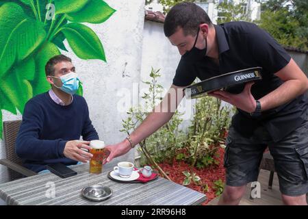 210530 -- BRÜSSEL, 30. Mai 2021 -- Luke Nolan R serviert einem Kunden ein Glas Bier in der Bar Funky Monkey in Brüssel, Belgien, 28. Mai 2021. Für Bar-Manager Luke Nolan kam die Entscheidung der belgischen Regierung, dem Gastgewerbe ab dem 8. Mai die Wiedereröffnung von Terrassen im Freien zu gestatten, nicht zu früh. Zuvor überlebten Luke und seine Kollegen monatelang hartes Management der Bar aufgrund der COVID-19-Pandemie und versorgten abends Essen zum Mitnehmen. Es war eine große Erleichterung für alle und ausgezeichnet für uns, wieder an die Arbeit und ausgezeichnet für unsere psychische Gesundheit. Für Menschen Stockfoto