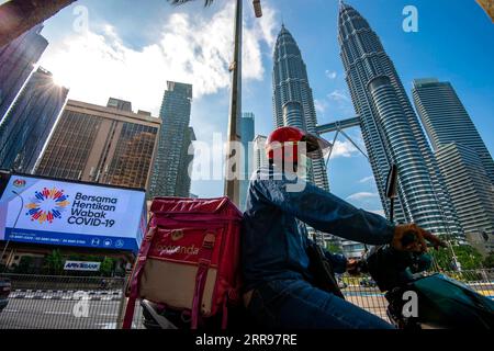 210601 -- KUALA LUMPUR, 1. Juni 2021 -- Ein Liefermann passiert einen elektronischen Bildschirm mit Anzeigen gegen COVID-19 in Kuala Lumpur, Malaysia, 1. Juni 2021. Malaysia hat am Dienstag landesweit eine zweiwöchige Sperrung eingeleitet, um die COVID-19-Infektionen zu reduzieren. Es dürfen nur wesentliche Sektoren betrieben werden, und es bestehen Reisebeschränkungen, um die Menschen in einem Umkreis von 10 km um ihre Häuser zu halten. Foto von /Xinhua MALAYSIA-COVID-19-NATIONWIDE LOCKDOWN ChongxVoonxChung PUBLICATIONxNOTxINxCHN Stockfoto