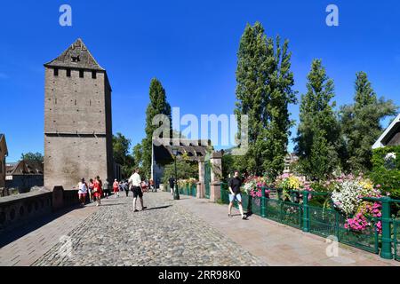 Straßburg, Frankreich - September 2023: Menschen überqueren die wunderschöne historische Brücke Ponts Couvert mit Turm an sonnigen Tagen Stockfoto