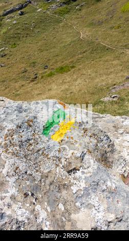 Farbige gelbe grüne Linie markierte Wanderwegschild und Wanderwege Bergschilder Pfad in Mauersteinen Stockfoto