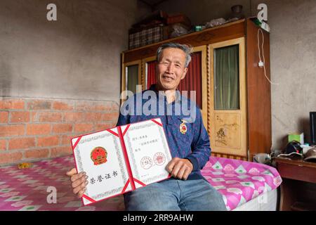 210606 -- YICHUN, 6. Juni 2021 -- Zhang Yingshan zeigt das Zertifikat des nationalen Modellarbeiters, den er zu Hause in einem Waldbauernhof erhalten hat, der vom Forstbüro Wumahe in der Stadt Yichun, Provinz Heilongjiang im Nordosten Chinas, am 3. Juni 2021 verwaltet wird. Sein ganzes Leben lang hat Zhang Yingshan, 65, seit über 45 Jahren mit Bäumen gearbeitet. Nach dem Schritt seines Vaters wurde Zhang 1975 Forstarbeiter im Forstbüro Wumahe. Neun Jahre später eröffnete er die erste familiengeführte Waldfarm des Büros und pflanzte jedes Jahr 30 Hektar Bäume. Von 1981 bis 2011 pflanzten Zhang und seine Frau Yan Yuping Stockfoto
