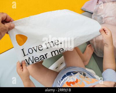 Hamburg, Deutschland - 24. Juli 2023: Überkopfansicht eines Erwachsenen, der einem Kleinkind einen Plastikbeutel mit dem Logo von Zalando und dem Slogan Love Me Weaar Me zeigt Stockfoto