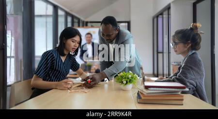 Positiv freundlicher Afro-amerikanischer Englischlehrer, der Sprachkurse für interessierte Erwachsene verschiedener Altersgruppen und Nationalitäten anbietet Stockfoto