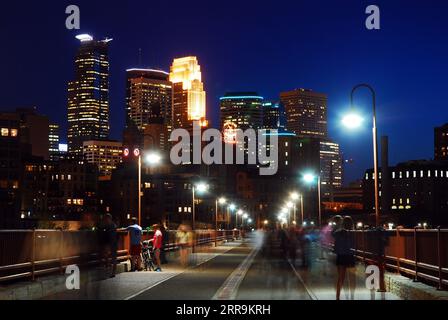 Ein nächtlicher Spaziergang entlang der Stone Arch Bridge, der zur Skyline von Minneapolis führt Stockfoto