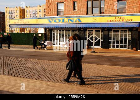 Eine kleine Gruppe von Menschen trotzt der Kälte und schlendert über die Promenade im russischen Viertel Brighton Beach, Brooklyn, New York City Stockfoto