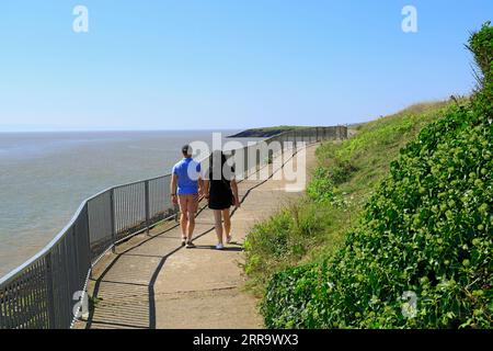 Ein Paar spaziert auf einem Küstenwanderweg zwischen Jacksons Bay und Whitmore Bay, Barry Island, Vale of Glamorgan, South Wales, UK. Stockfoto