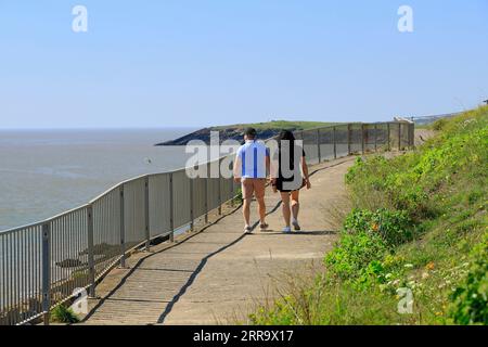 Ein Paar spaziert auf einem Küstenwanderweg zwischen Jacksons Bay und Whitmore Bay, Barry Island, Vale of Glamorgan, South Wales, UK. Stockfoto