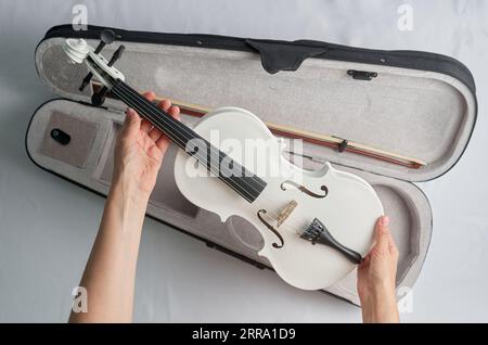 Die Hand einer Frau nimmt eine weiße Violine aus ihrem Fall Stockfoto