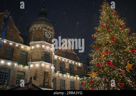 Spektakulärer Blick auf das Düsseldorfer Rathaus und den Weihnachtsmarkt mit schneebedecktem Weihnachtsbaum. Das Bild wurde bei leichtem Schneefall mit einem sensationellen Nachthimmel aufgenommen. Stockfoto