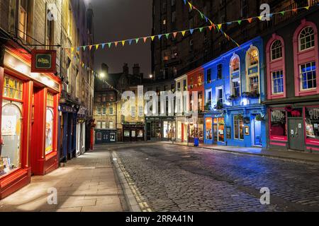 Victoria Street und West Bow bei Nacht in Edinburgh, Schottland. Malerische gewundene Straße in der Altstadt mit bunten Gebäuden und Einzelhandelsstor Stockfoto