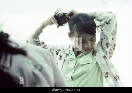 Junge Vietnamesin, die ihr Haar zusammengebunden hat, bevor sie den Helm aufsetzt Stockfoto