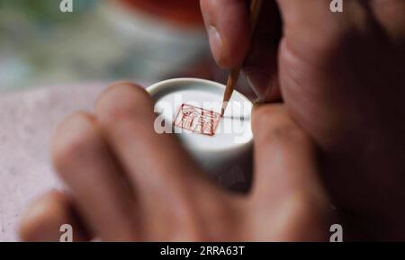 210717 -- JINGDEZHEN, 17. Juli 2021 -- Cheng Xiaoqian malt in einem Studio in Jingdezhen, ostchinesische Provinz Jiangxi, 13. Juli 2021 auf einen Guyacai-Porzellanbecher. Guyacai, wörtlich übersetzt „malerische Farbdekoration“ auf Chinesisch, ist eine Art Porzellandekoration, die in den 1980er Jahren erfunden wurde Seine Spezialität liegt in einer Kombination aus chinesischer Kunst und westlichen Gemälden. Ein Guyacai-Maler muss nicht nur gut über Pigmentmerkmale Bescheid wissen, sondern auch die Fähigkeiten in westlicher und traditioneller chinesischer Malerei, Kalligraphie und Dichtung beherrschen, um die Schönheit der klassischen und malerischen Kunst auszudrücken Als Sohn von Guy Stockfoto