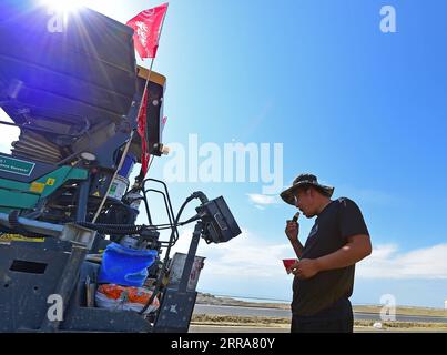 210720 -- FUHAI, 20. Juli 2021 -- Ein Arbeiter isst Wassermelone, um sich auf einer Baustelle einer Schnellstraße durch die Wüste in der autonomen Region Xinjiang Uygur im Nordwesten Chinas abzukühlen, 16. Juli 2021. Der Bau der ersten Schnellstraße über die Wüste in Xinjiang verlief reibungslos. Die Schnellstraße, die die Präfektur Altay mit der regionalen Hauptstadt Ürümqi verbindet, erstreckt sich über etwa 343 km, wobei Abschnitte von mehr als 150 km durch die Wüste gebaut werden. CHINA-XINJIANG-CROSS-DESERT EXPRESSWAY-BAU CN HOUXZHAOKANG PUBLICATIONXNOTXINXCHN Stockfoto