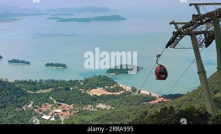 Luftaufnahme von Langkawi, Malaysia, mit einer Seilbahn, die zum Himmel über dem blauen Meer mit üppigen grünen Bäumen aufsteigt Stockfoto