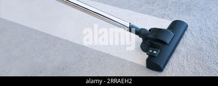 Starker Staubsauger, der einen sauberen Streifen auf einem grauen Teppich erzeugt und Hausstaubmilben beseitigt, die Allergien und unhygienischen Schmutz verursachen, Panoramaformat, Stockfoto