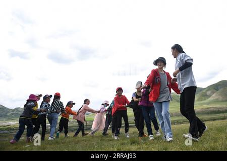 210803 -- GOLOG, 3. August 2021 -- Kinder spielen ein Spiel, das von Freiwilligen von Studenten in einer Kindertagesstätte in Nyainca Village im Maqen County, Golog Tibetan Autonomous Prefecture, in der nordwestlichen chinesischen Provinz Qinghai, 2. August 2021, geführt wird. Nyainca Village liegt am Fuße des Berges A nyemaqen in der nordwestlichen chinesischen Provinz Qinghai. Da die örtlichen Hirten mit dem Umzug auf die Sommerweiden beschäftigt sind, können ihre Kinder im schulpflichtigen Alter während der Sommerferien Schwierigkeiten haben, an Gruppenaktivitäten teilzunehmen, und einige werden sogar unbeaufsichtigt gelassen. Im Jahr 2018 haben die lokalen Behörden ein Pro gestartet Stockfoto