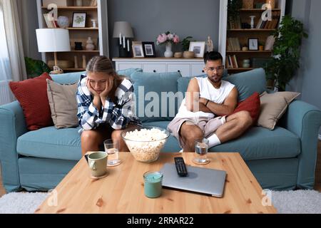 Junge Paare streiten sich auf der Couch in ihrem Haus und haben Schwierigkeiten und Probleme in einer Beziehung und Ehe, die sich Rücken an Rücken lehnen und ein ignorieren Stockfoto