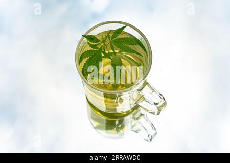 Marihuana-Tee. Hanftee. Cannabis Tee in Glas Teetasse mit einem Marihuana Blatt und Stängel mit Blumen und Blättern. Stockfoto