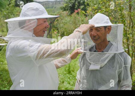 210821 -- FUZHOU, 21. August 2021 -- Wu Panfeng L arrangiert Gesichtsschutz für seinen Vater im Dorf Xiangyang in der Stadt Nan, Provinz Fujian im Südosten Chinas, 12. August 2021. Wu Panfeng kehrte vor ein paar Jahren ins Dorf Xiangyang zurück und nutzte das Internet-Marketing-Wissen, das er lernte, um sein Honiggeschäft zu betreiben. Im Jahr 2017 schlug China eine Strategie zur ländlichen Belebung als Schlüsselmaßnahme zur Beschleunigung der Modernisierung der Landwirtschaft und der ländlichen Gebiete vor und hat seither eine Vielzahl von Strategien verabschiedet, um den Fahrplan für die ländliche Belebung festzulegen. Mit der Vertiefung der Kampagne wurden immer mehr junge, hochqualifizierte Mitarbeiter eingesetzt Stockfoto