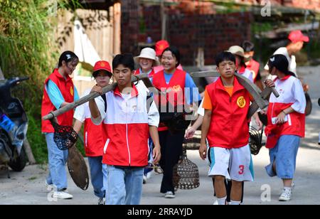 210822 -- RONGSHUI, 22. August 2021 -- Schüler sammeln alte landwirtschaftliche Werkzeuge und Lebensgeräte im Dorf Wuying, das an der Grenze zwischen der südchinesischen autonomen Region Guangxi Zhuang und der südwestchinesischen Provinz Guizhou liegt, am 21. August 2021. Im Sommer 2021 führte ein ehrenamtliches Team aus Studenten und Mittelschülern die lokalen Schüler zu verschiedenen Aktivitäten wie der Pflege von Setzlingen, dem Erlernen immaterieller Kulturgüter und dem Sammeln alter landwirtschaftlicher Werkzeuge für Museen. CHINA-GUANGXI-WUYING DORF-STUDENTEN SOMMERURLAUB CN HUANGXXIAOBANG PUBLICATIONXNOTXINXC Stockfoto