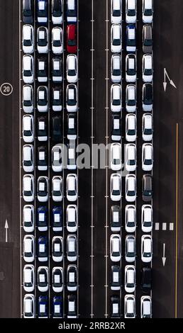 An aerial view directly above rows of newly built cars in the automobile industry on a commercial dock ready to be loaded for export and import Stock Photo