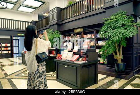 210829 -- XI AN, 29. Aug. 2021 -- Eine Frau fotografiert im Bell Tower Bookstore in Xi an, Provinz Shaanxi im Nordwesten Chinas, 25. Aug. 2021. Der Bell Tower Bookstore wurde 1955 als erste staatliche Buchhandlung in Xi an erbaut und war als kulturelles Wahrzeichen der Stadt bekannt. Um das kulturelle Erbe zu schützen, wurde 2008 der Buchladen an einen anderen Ort verlegt. Vor kurzem wurde der Bell Tower Bookstore nach der Instandhaltung wieder an seine ursprüngliche Stelle gebracht, wodurch sein ursprüngliches Aussehen in den 1950er Jahren im Wesentlichen wiederhergestellt wurde, so dass Bürger und Touristen das historische an wieder erleben können Stockfoto