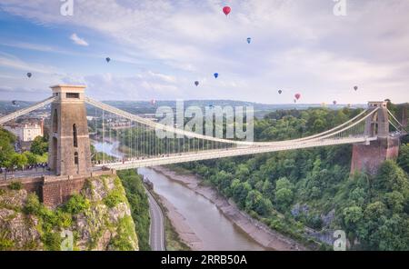 Der Massenaufstieg bei der Bristol International Balloon Fiesta, während farbenfrohe Heißluftballons über die Clifton Suspension Bridge in die Luft fliegen. Stockfoto