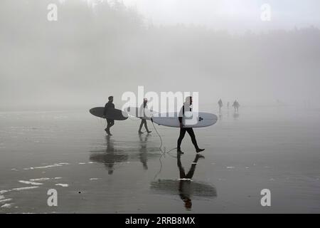 Surfer, die in Neoprenanzügen gekleidet sind, begeben sich am Indian Beach im Ecola State Park entlang der Küste von Oregon in der Nähe von Cannon Beach, Oregon, aufs Wasser. Stockfoto