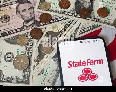 Deutschland. September 2023. In dieser Abbildung wird das Logo der State Farm Mutual Automobile Insurance Company auf einem Smartphone und US-Banknoten und -Münzen im Hintergrund angezeigt. (Bild: © Igor Golovniov/SOPA Images via ZUMA Press Wire) NUR REDAKTIONELLE VERWENDUNG! Nicht für kommerzielle ZWECKE! Stockfoto