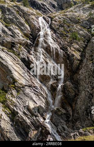 Ein herrlicher, kaskadenartiger Wasserfall fließt einen felsigen Hügel hinunter und schafft eine erfrischende und ruhige Atmosphäre Stockfoto