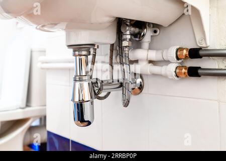 Verbindung von Polypropylen- und flexiblen Polyethylen-Kunststoffrohren unter dem Waschbecken im Toilettenraum Stockfoto