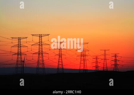 211013 -- YINCHUAN, 13. Oktober 2021 -- das Foto zeigt Anlagen des 660 kV-Hochspannungs-Gleichstrom-HGÜ-Übertragungsprojekts von Yindong bei Sonnenuntergang in der autonomen Region Ningxia Hui im Nordwesten Chinas. Xinhua Schlagzeilen: Schnellstraßen treiben die CO2-Emissionsreduzierung in China voran JinxHe PUBLICATIONxNOTxINxCHN Stockfoto
