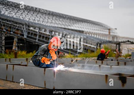 211016 -- QIAN AN, 16. Oktober 2021 -- Ein Arbeiter schweißt Baumaterialien auf der Baustelle eines Straßen-Schienen-Projekts in Qian an Ctiy, nordchinesische Provinz Hebei, 16. September 2021. Qian an in der Provinz Hebei ist ein wichtiger Bezirk in der Stahlindustrie in Nordchina, mit einer großen Nachfrage nach Rohstoffen wie Eisenerz, Kohle und Koks. Um die Verschmutzung und die Verkehrsüberlastung durch den Straßentransport von Massengütern zu verringern, wurden spezielle Eisenbahnlinien für wichtige Eisen- und Stahlunternehmen im Rahmen eines „Road-to-Rail“-Systems gebaut, das den Weg für eine umweltfreundlichere und effizientere Entwicklung ebnete Stockfoto