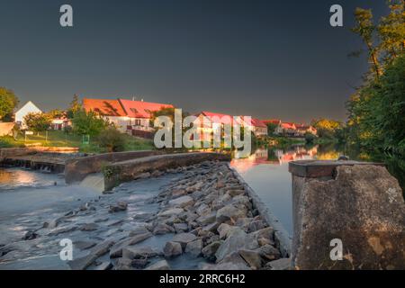 Großes Wehr in Budweis mit blauem Himmel und kleinen Gebäuden auf dem Land bei Sonnenuntergang am heißen Abend Stockfoto