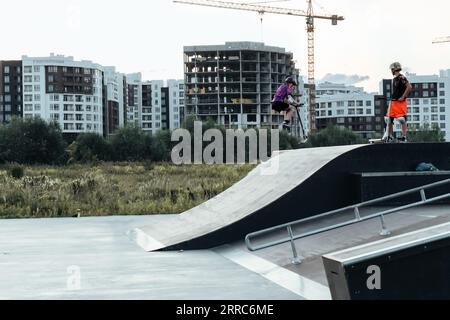 Aktive Freizeitgestaltung für Kinder auf einem Roller. Ein Junge auf einem Roller in einem Skatepark führt Sprünge und Tricks durch. Extremes Springen auf einem Roller. Stockfoto