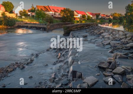 Großes Wehr in Budweis mit blauem Himmel und kleinen Gebäuden auf dem Land bei Sonnenuntergang am heißen Abend Stockfoto