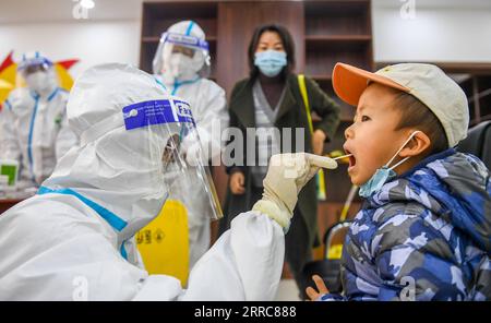 211024 -- HOHHOT, 24. Oktober 2021 -- Ein medizinischer Mitarbeiter nimmt eine Abstrichprobe von einem Kind an einem temporären Nukleinsäure-Testgelände in Hohhot, Nordchina, Autonome Region Innere Mongolei, 24. Oktober 2021. Um die Ausbreitung von COVID-19 einzudämmen, hat die Stadt Hohhot Nukleinsäuretests für Bewohner aus Schlüsselregionen und alle Menschen, die Hohhot mit dem Flugzeug, dem Zug, dem Shuttlebus, dem Taxi, Privatwagen und anderen Transportmitteln betreten und verlassen, eingeleitet. CHINA-INNERE MONGOLEI-HOHHOT-COVID-19-TESTSCN PENGXYUAN PUBLICATIONXNOTXINXCHN Stockfoto