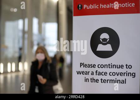 211201 -- LONDON, 1. Dez. 2021 -- Ein Passagier geht an einem Gesundheitshinweis im Flughafen Heathrow in London, Großbritannien, 30. November 2021 vorbei. Der britische Premierminister Boris Johnson sagte am Samstag, dass alle Reisenden, die nach Großbritannien einreisen, bis zum Ende des zweiten Tages nach ihrer Ankunft einen PCR-Test machen müssen und sich selbst isolieren müssen, bis sie ein negatives Testergebnis erhalten. Passagiere, die ab 0400 Uhr (GMT) am 28. November aus Ländern der roten Reiseroute Großbritanniens, einschließlich Südafrika, in Großbritannien ankommen, müssen ein von der Regierung genehmigtes Hotel buchen und bezahlen, damit es 10 Tage lang unter Quarantäne gestellt werden kann. Omicron, eine neue COVID-19-Variation Stockfoto