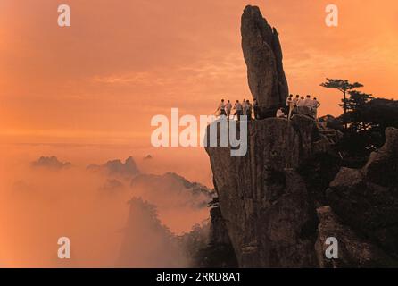 Chinesen in der Abenddämmerung am Felsen, die von Afar auf dem Mount Huangshan (gelber Berg) in der Provinz Anui, China, flogen. Stockfoto