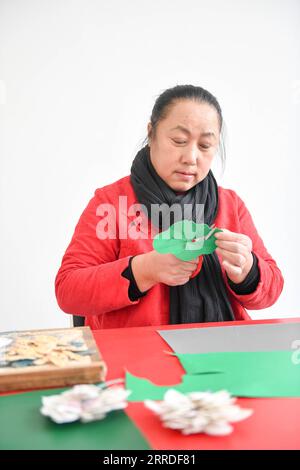 211222 -- CHANGCHUN, 22. Dezember 2021 -- Li Baofeng schafft Papierschneidearbeiten in Changchun, nordöstliche Provinz Jilin, 17. Dezember 2021. Li Baofeng, 56, ist ein Papierschneider in Jilin. Durch die Kombination traditioneller Papierschneidetechnik mit Merkmalen verschiedener Malformen wie der chinesischen Malerei, Ölmalerei und Druckerei kreiert Li ihren eigenen Kunststil. Ihre Werke sind farbenreich und stark im dreidimensionalen Sinne. Die meisten ihrer Kreationen konzentrieren sich auf die klassische chinesische Literatur, Volksbräuche und Landschaften. Eine ihrer Arbeiten Chinese Red zeigt eine Reihe von Geschichten über die Stockfoto