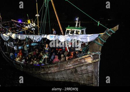 211231 -- ACEH, 31. Dezember 2021 -- Rohingya-Flüchtlinge sitzen auf einem Holzboot, während indonesische Beamte im Hafen Krueng Geukueh in Lhokseumawe, Aceh, Indonesien, am 31. Dezember 2021 evakuieren. Die indonesische Marine hat mehr als 100 Rohingya-Asylsuchende gerettet, die auf einem sinkenden Boot vor der Westküste des Landes herumgerissen sind und sie an einen vorübergehenden Ort gebracht haben. Foto von /Xinhua INDONESIA-ACEH-ROHINGYA-REFUGEES-EVAKUATION FachrulxReza PUBLICATIONxNOTxINxCHN Stockfoto