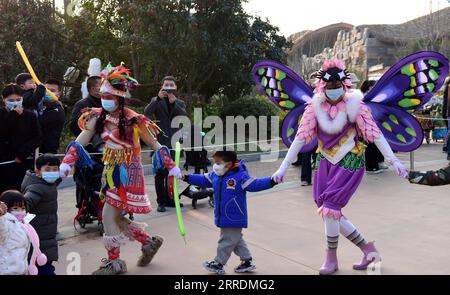 220103 -- ZHENGZHOU, 3. Januar 2022 -- Kinder interagieren mit Performern in einem Tierpark in Zhengzhou, Provinz Henan in Zentralchina, 2. Januar 2022. CHINA-URLAUB-UNTERHALTUNG ZhuxXiang PUBLICATIONxNOTxINxCHN Stockfoto