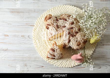 Köstlicher italienischer Ostertaubenkuchen (traditionell Colomba di Pasqua) und festliches Dekor auf weißem Holztisch, Blick von oben. Platz für Text Stockfoto