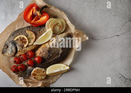 Köstlicher dorado-Fisch mit Gemüse, serviert auf hellgrauem Tisch, Blick von oben. Leerzeichen für Text Stockfoto