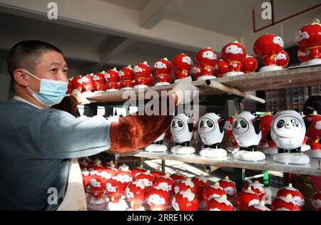 220119 -- DEHUA, 19. Januar 2022 -- Ein Arbeiter stellt neu gefertigte Porzellanfiguren von Peking 2022 Maskottchen auf das Regal in einer Porzellanfabrik in Dehua County Quanzhou, südöstliche Provinz Fujian, 19. Januar 2022. CHINA-FUJIAN-BEIJING 2022 MASKOTTCHEN-PORZELLAN CN WEIXPEIQUAN PUBLICATIONXNOTXINXCHN Stockfoto