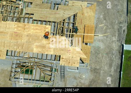 Bauarbeiter, die an der Dachkonstruktion eines unfertigen Wohnhauses mit Holzrahmenstruktur im Vorstadtgebiet von Florida arbeiten. Wohnungsbau Stockfoto